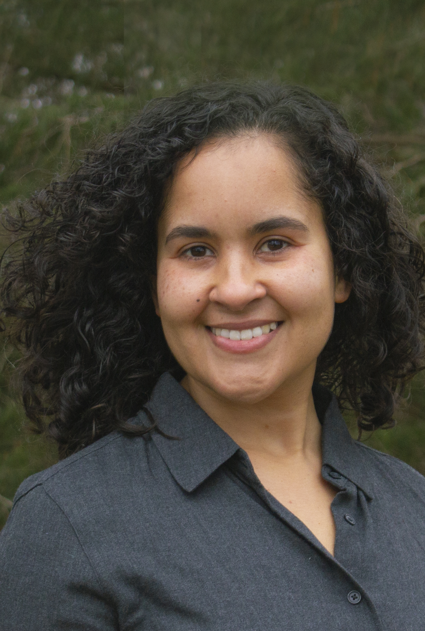 A woman smiles while standing outside